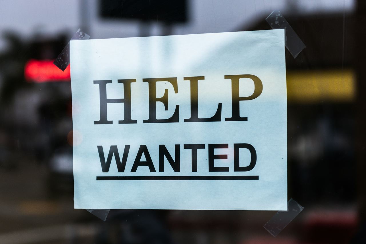 Une affiche « Help wanted », on recherche de l'aide, collée sur une vitrine.