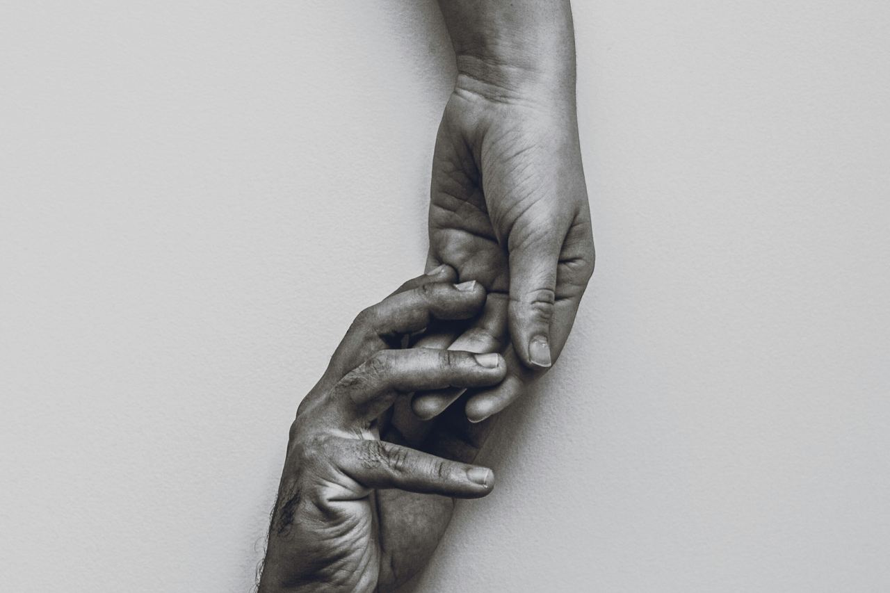 Deux mains se saisissent l'une l'autre, en noir et blanc.