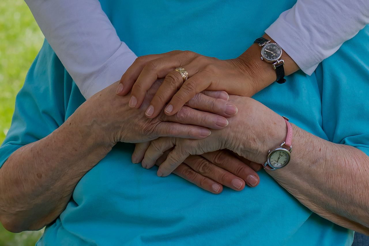 Les mains d'une personne jeune posées sur celles d'une personne âgée.
